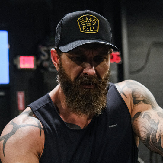 GBRS Group Hard To Kill Trucker Hat. Richardson 112FP with Classic Trucker vibes. Front of hat. Lifestyle image in a gym