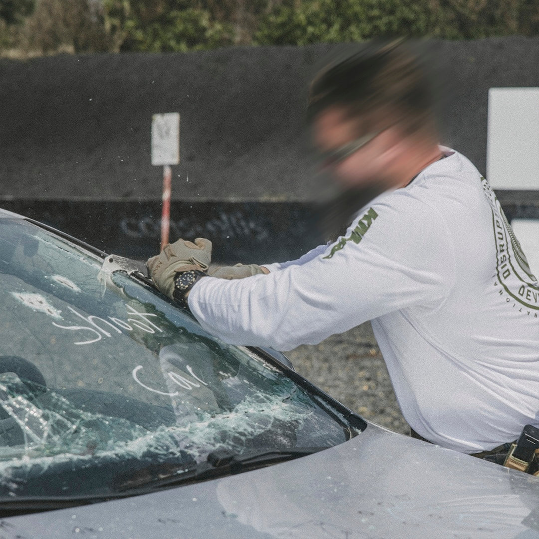 Person cutting into a car windshield with a sharp black metal tool bar.