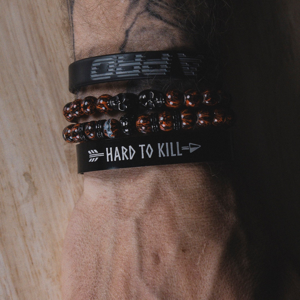 Close up of a person wearing GBRS Group Hard to Kill Cuff on wrist among other bracelets and accessories 
