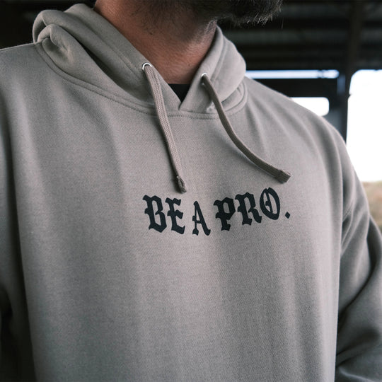 GBRS Group Be A Pro Pull Over Hoodie - Front design view in lifestyle range environment. Be A Pro - A mindset to elevate your performance, keep you focused, and help spark motivation in others to foster the same mentality. 