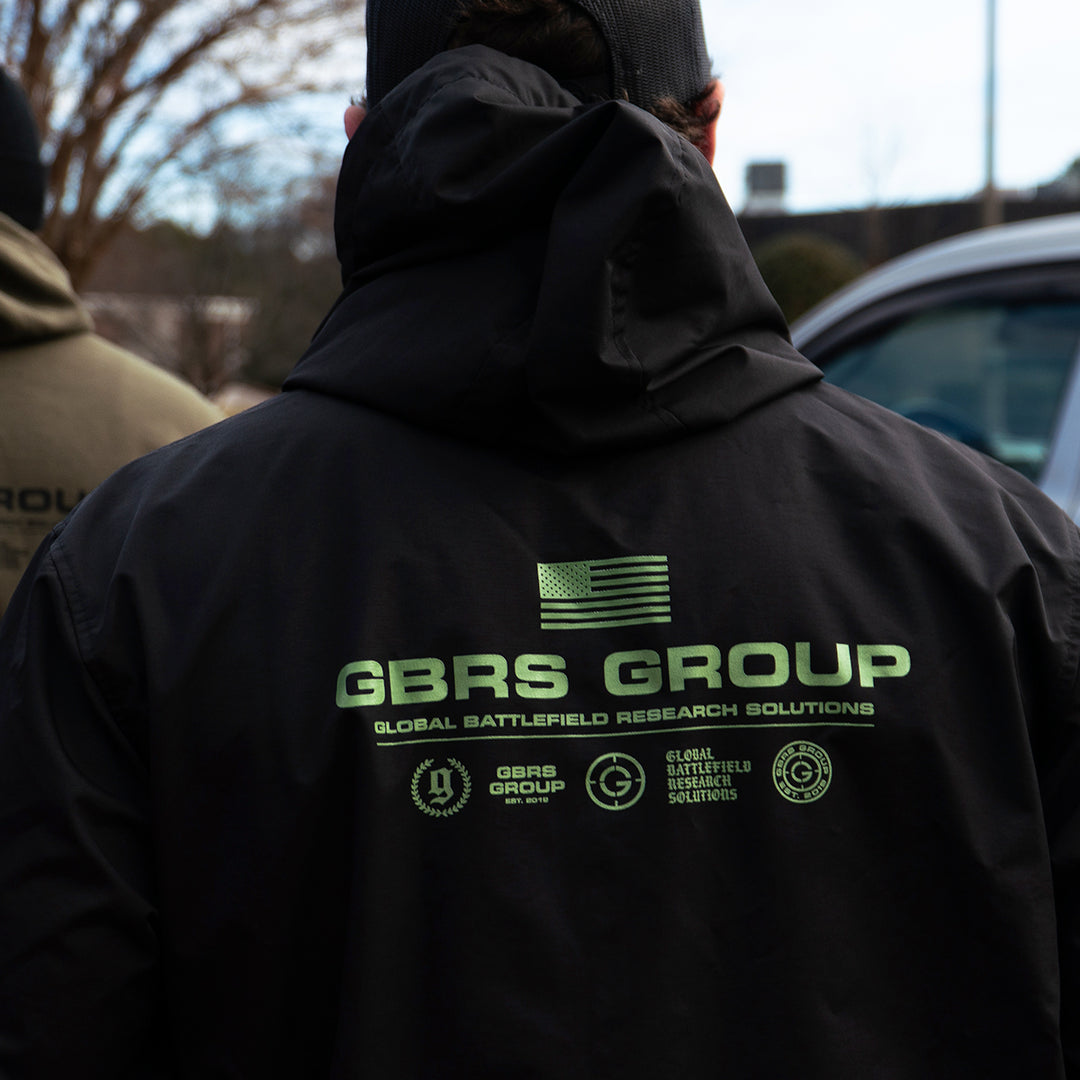 GBRS Group Instructor Rain Jacket - Anniversary Edition with  Level 3 waterproofing. Black with Green ink. - LIfestyle image outdoors