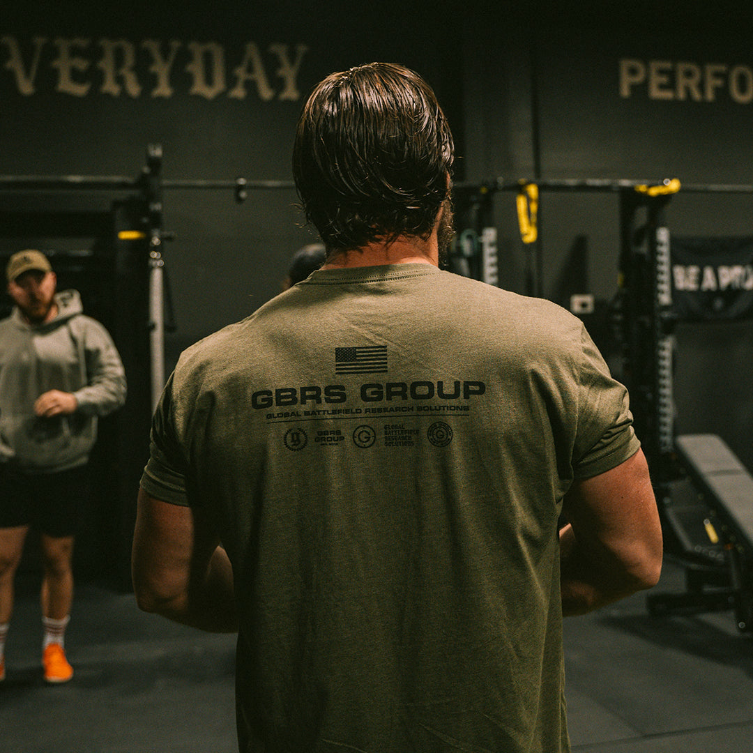 GBRS Group Instructor Short Sleeve Shirt - Anniversary Edition in Green with Black print. Features Slightly tapered athletic fit. Screen printed GBRS GROUP Anniversary Edition back print graphic. Screen printed center chest GBRS GROUP graphic. Lifestyle image in the gym