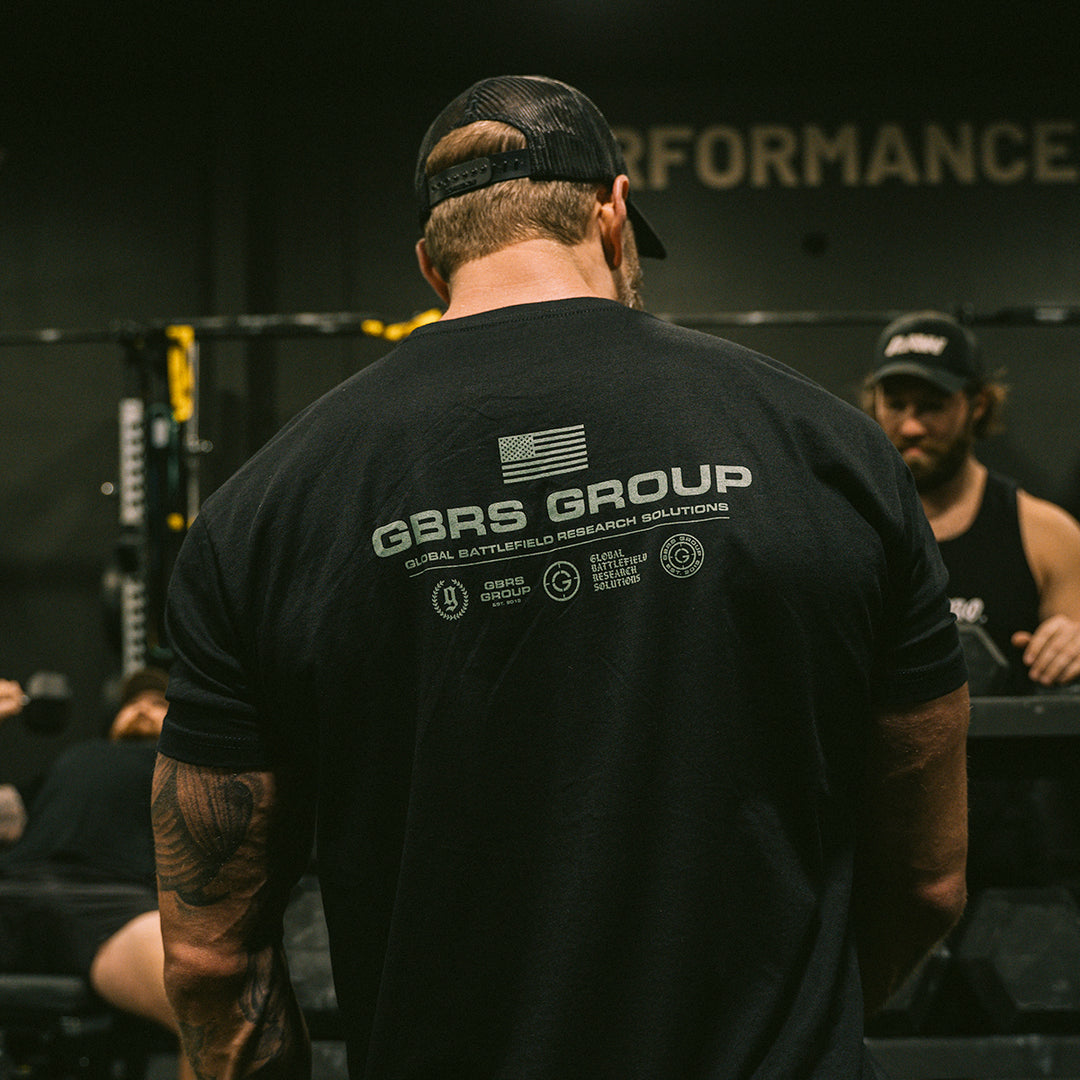 GBRS Group Instructor Short Sleeve Shirt - Anniversary Edition in Black with Green print. Features Slightly tapered athletic fit. Screen printed GBRS GROUP Anniversary Edition back print graphic. Screen printed center chest GBRS GROUP graphic. Lifestyle image in the gym