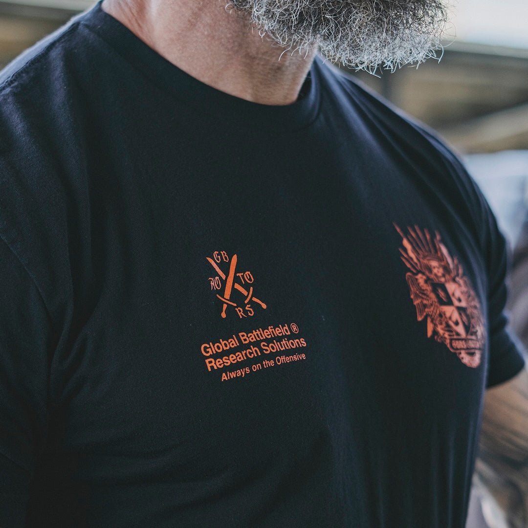 Person wearing a black t-shirt with red-orange text and designs on right and left pocket