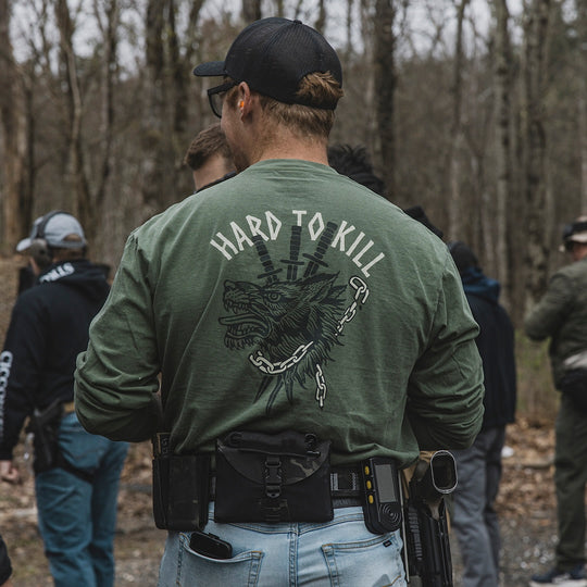 Model wearing the GBRS Group Hard to Kill Long Sleeve in an outdoor range setting, showing the back design