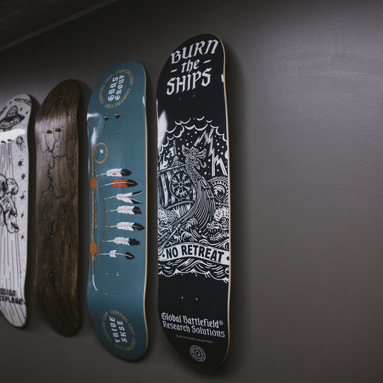 GBRS Group Burn The Ships Skateboard Deck lifestyle image pictured hanging on a wall with other skateboard decks