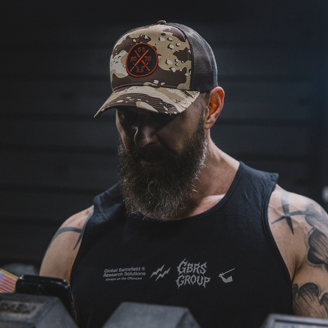 Man wearing a camouflage cap and black tank top in a gym setting