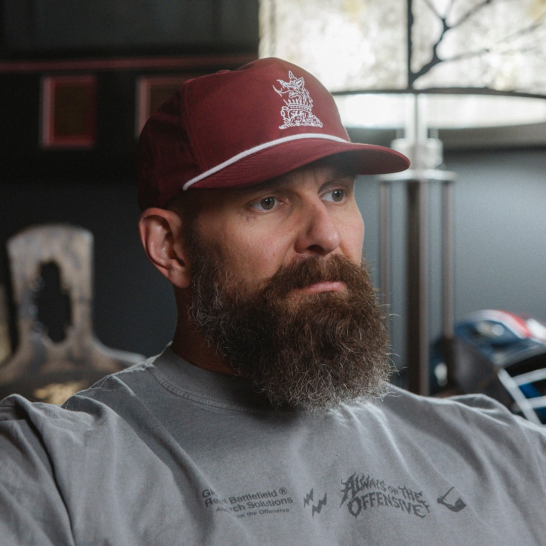 Man wearing a red and white cap and gray long sleeve in an indoor setting