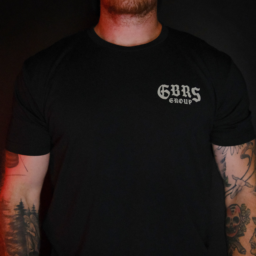 GBRS Group Hard To Kill Short Sleeve Shirt - Front of black tee shirt worn by a man with tatoos. 