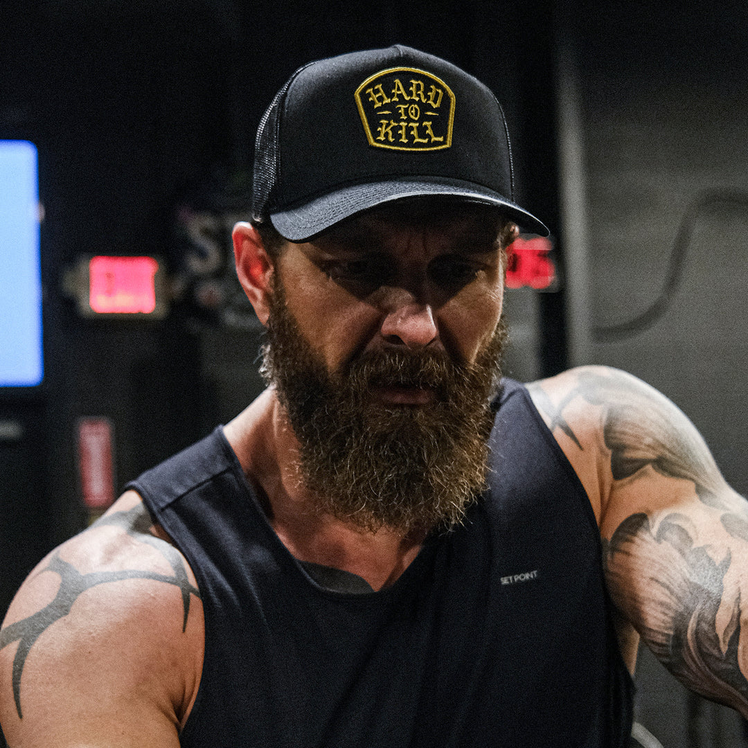 GBRS Group Hard To Kill Trucker Hat. Richardson 112FP with Classic Trucker vibes. Front of hat. Lifestyle image in a gym