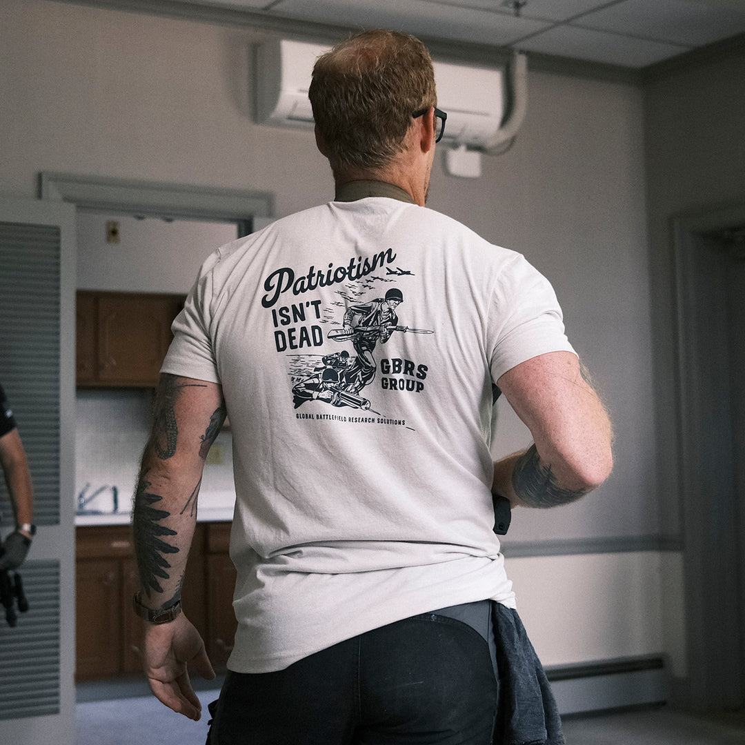 GBRS Group Storming The Beach Short Sleeve Shirt in tan with Black full back print shown in a lifestyle image inside an apartment type room