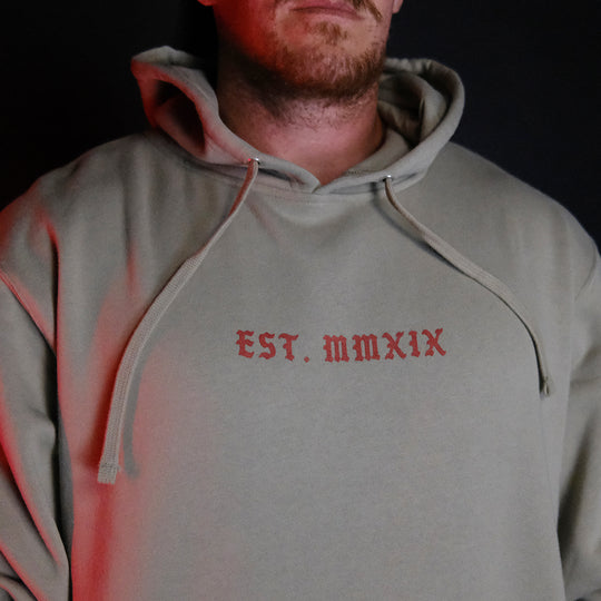 GBRS Group Triple Daggers Pullover Hoodie - Front of Cement colored hoodie on body in dark room