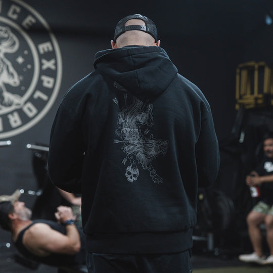 Man wearing the GBRS Group Hard to Kill Oversized Hoodie in a gym, showing the back design