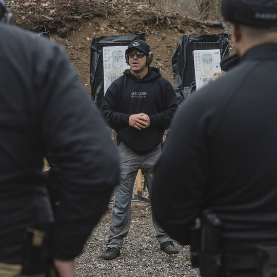 Man wearing the GBRS Group Hard to Kill Oversized Hoodie outdoors and instructing a group of others