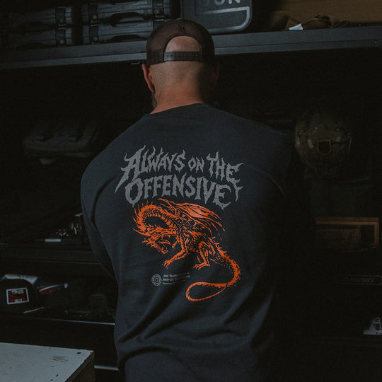 Person wearing a black long sleeve with 'Always on the Offensive' design in a garage setting