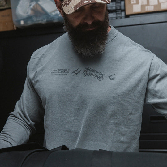 Man wearing a gray long sleeve with text and graphic designs on the front