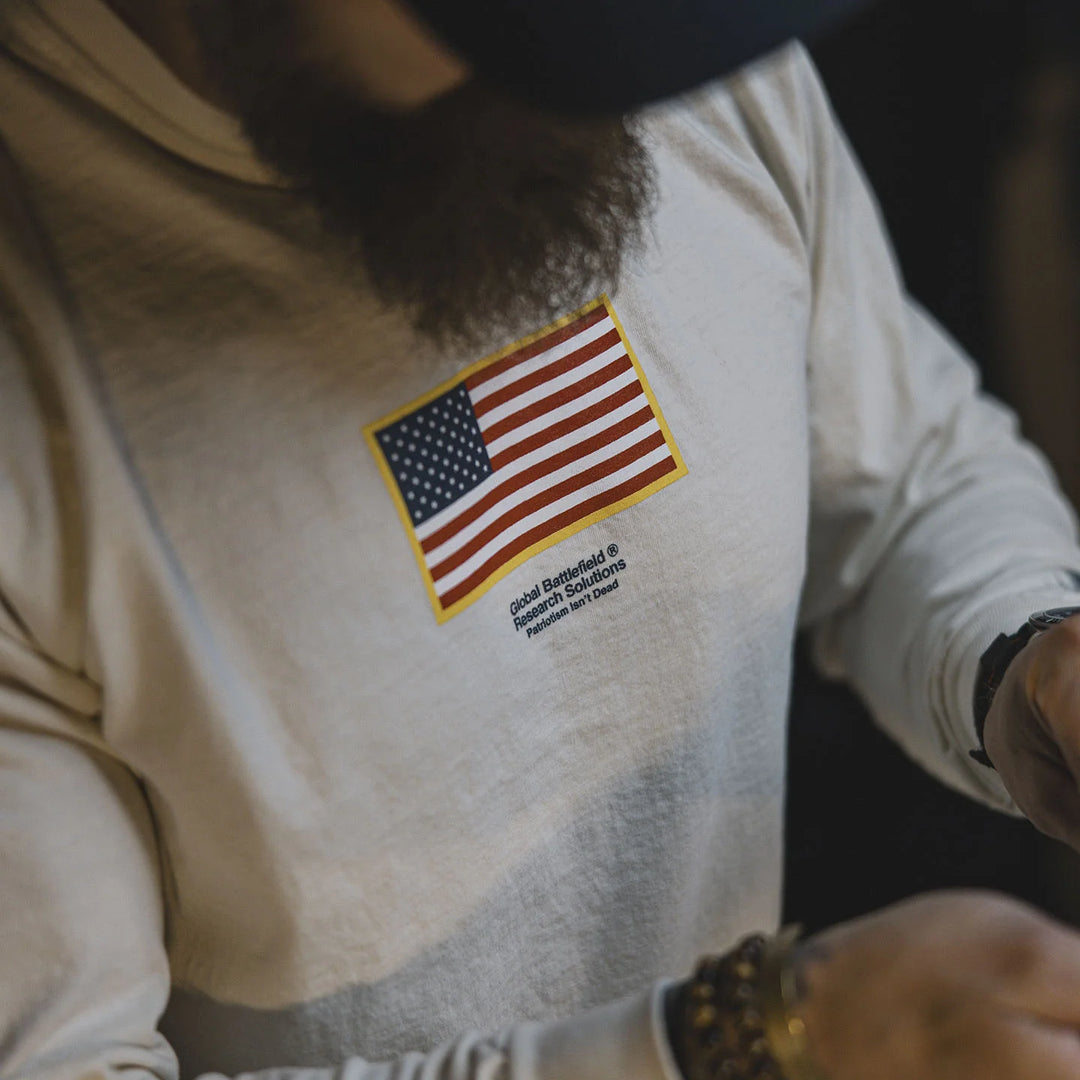 Person wearing the GBRS Group Front and Center Long Sleeve Shirt with an American flag patch on a dark background