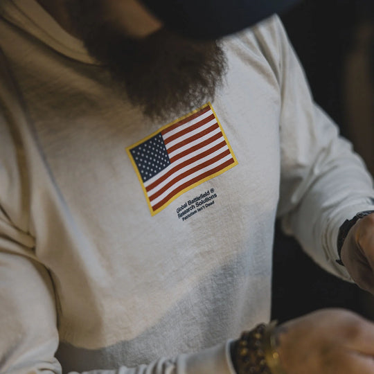 Person wearing the GBRS Group Front and Center Long Sleeve Shirt with an American flag patch on a dark background