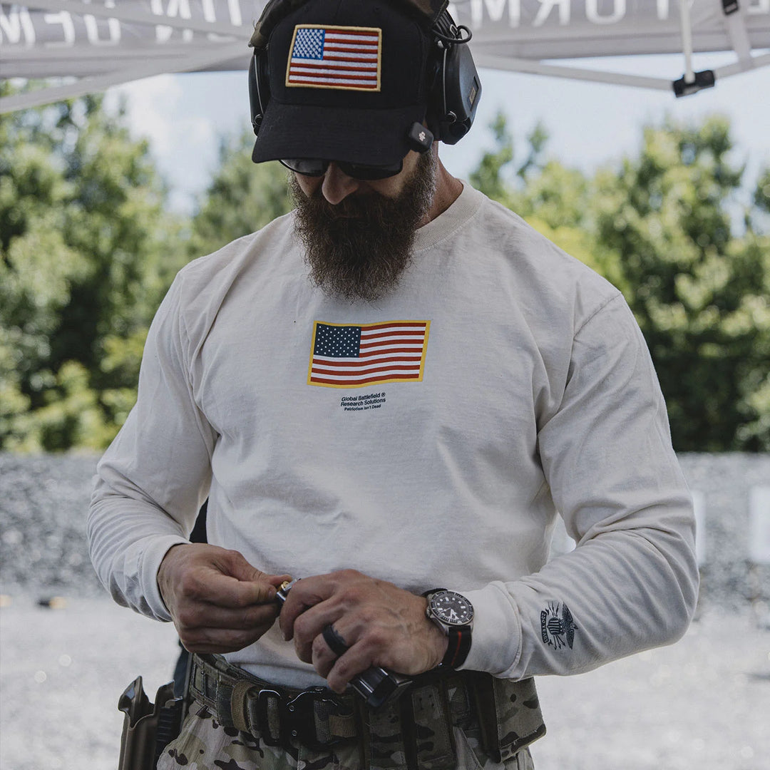 Man wearing the GBRS Group Front and Center Long Sleeve Shirt at an outdoor range while wearing a cap.