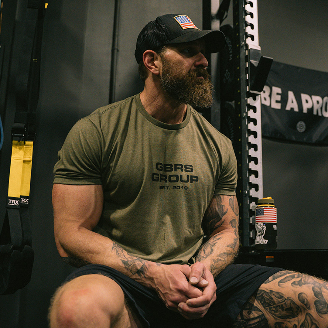 Man resting in the gym wearing a green GBRS t-shirt