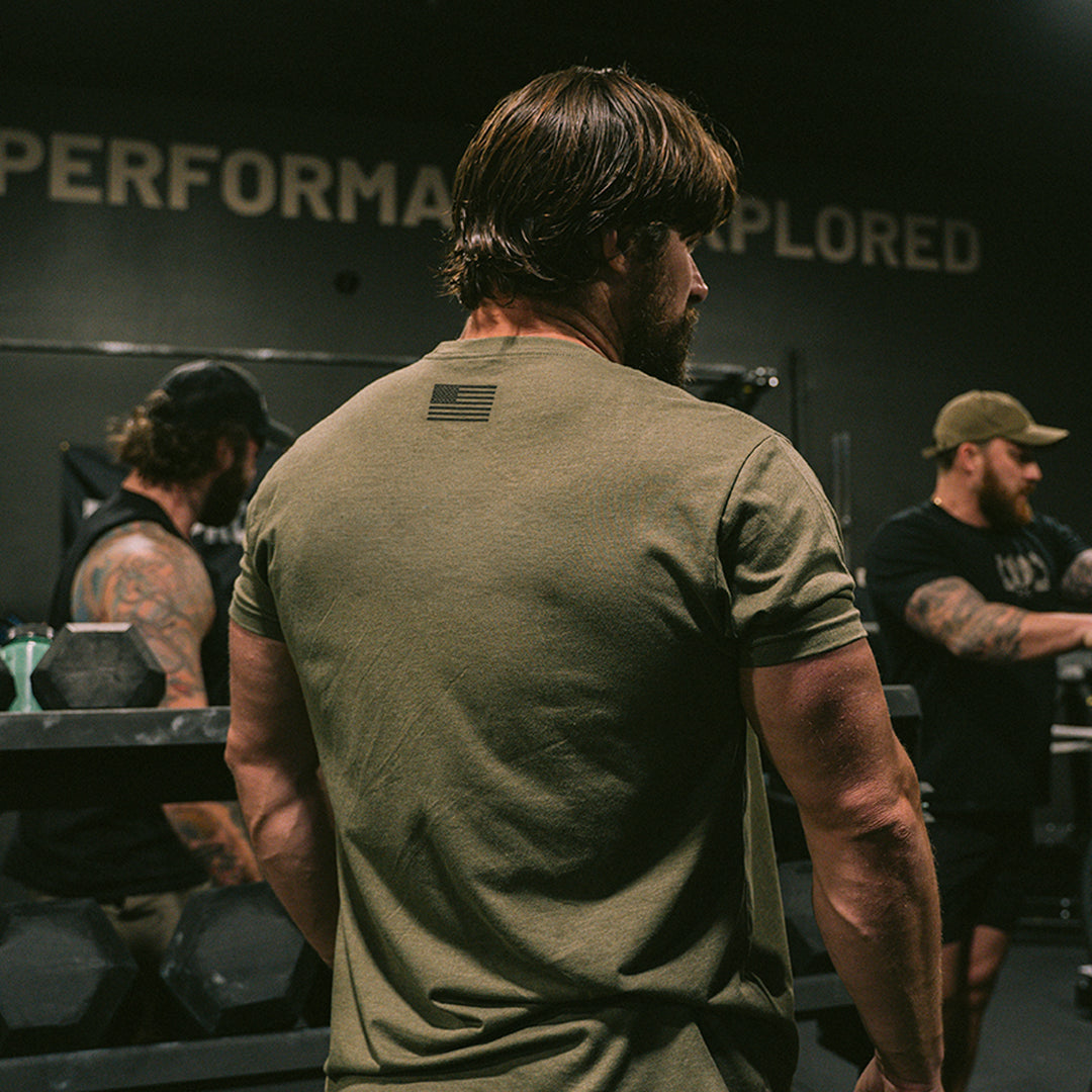 Person wearing a GBRS Group Instructor Short Sleeve Shirt talking to other people in the gym