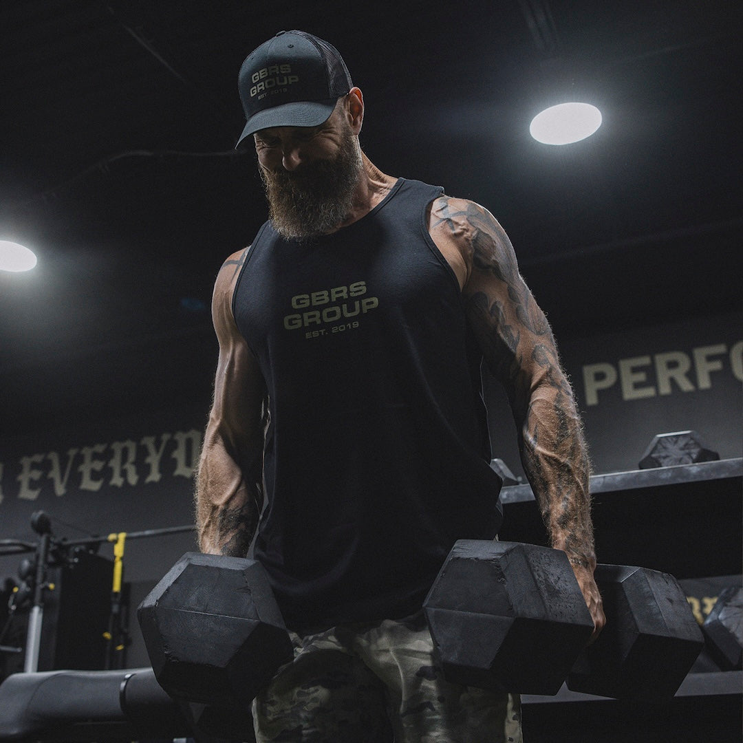 Man wearing GBRS Group Instructor Tank and holding 2 dumbbells in his hands