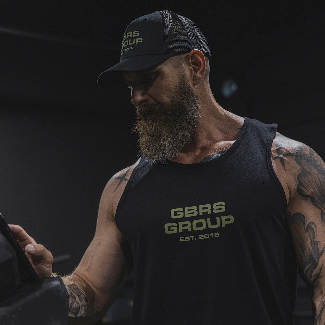 Man wearing a GBRS tank top and hat in the gym