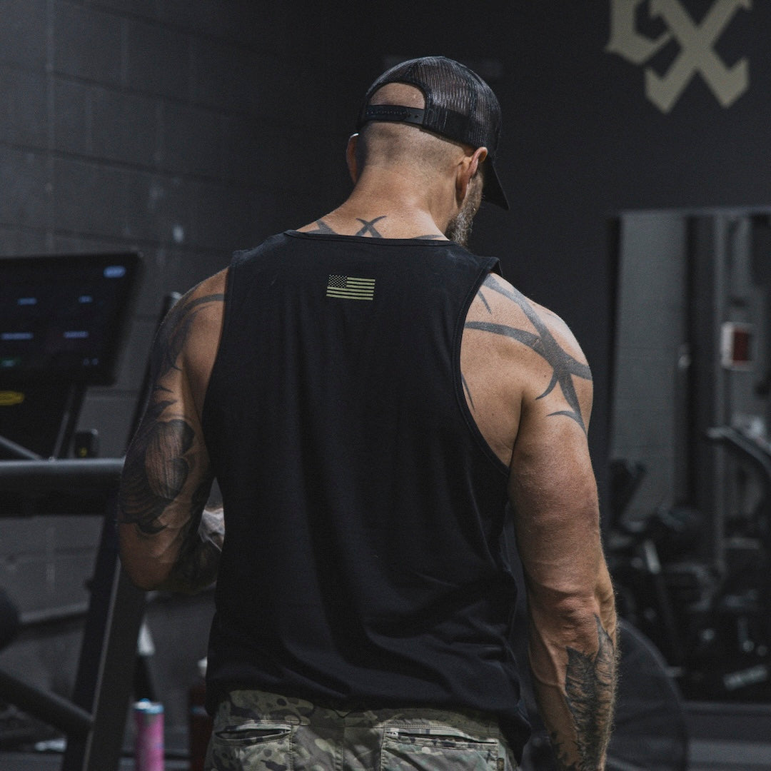 Athletic man wearing the GBRS Group Instructor Tank while performing exercises 