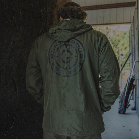 Man in an outdoor range showing the back design of the GBRS Group Instructor Windbreaker Jacket