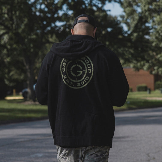Person walking outside while wearing the GBRS Group Instructor Zip Up Hoodie