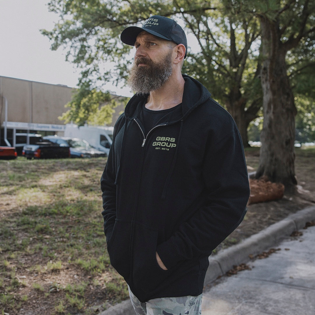Man walking outside wearing a GBRS zip up hoodie