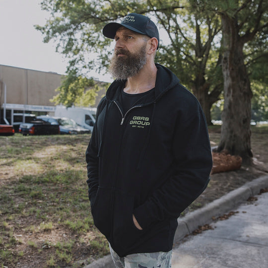 Man walking outside wearing a GBRS zip up hoodie