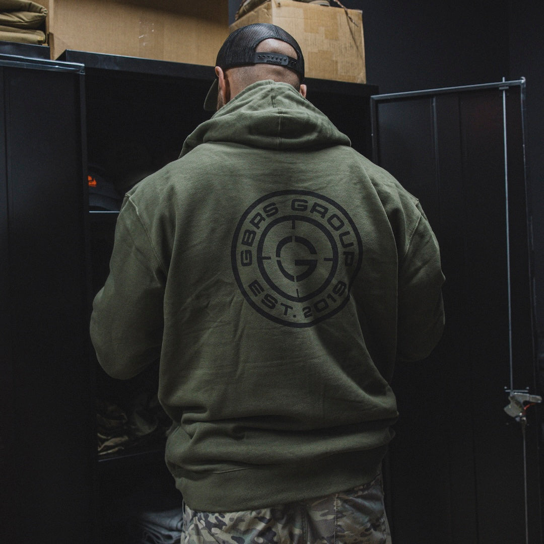 Person wearing the green GBRS Group Instructor Zip Up Hoodie and looking into a locker