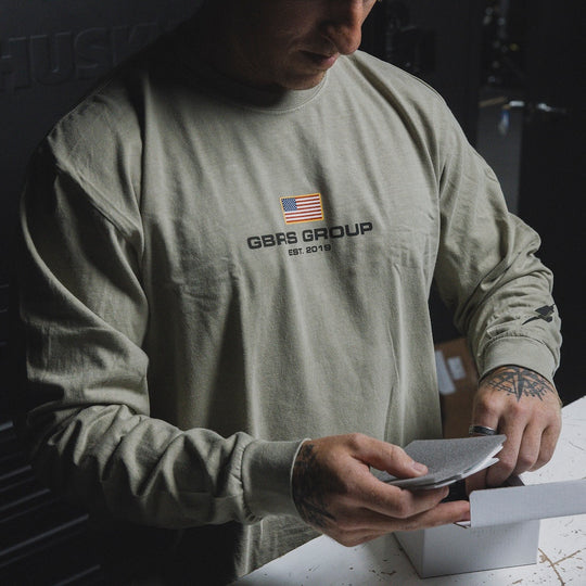Man going through a box while wearing the GBRS Group International Long Sleeve Shirt.