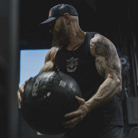 DJ Shipley performing an exercise while wearing the GBRS Group Lead and Lace Tank in the gym.