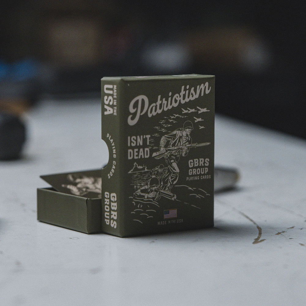 GBRS Group Patriotism Isn't Dead Playing Cards with 'Patriotism Isn't Dead' text and GBRS Group branding on a worktable.