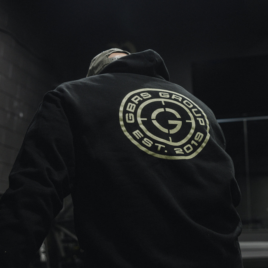 GBRS Group Instructor Pullover Hoodie, pictured in black in a gym lifestyle setting showing the backprint design