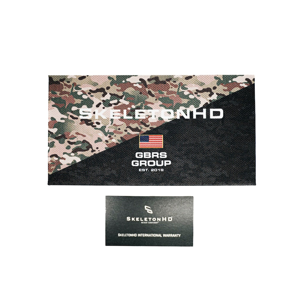 A rectangular branded box with a diagonal camouflage-and-black design, shown above a smaller black card reading SkeletonHD International Warranty. Visible text on box includes Skeleton HD and GBRS GROUP with a small American flag graphic.