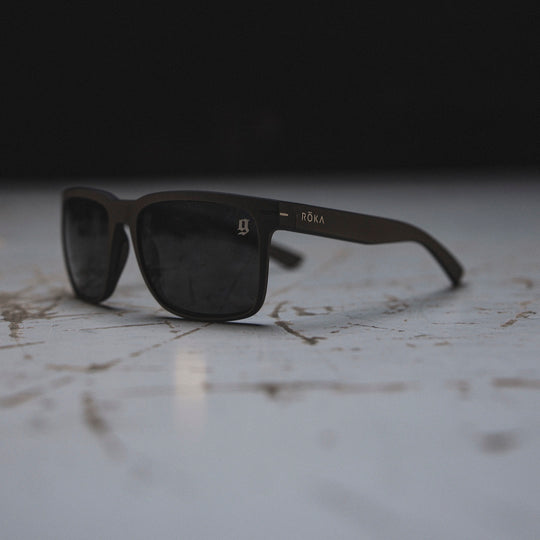 The GBRS Group  ROKA Barton polarized sunglasses resting on scratched desk with a dark background. 