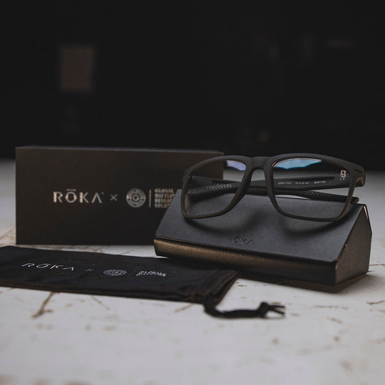 Black glasses with clear lens on a black case with GBRS Group and Roka branding in the background